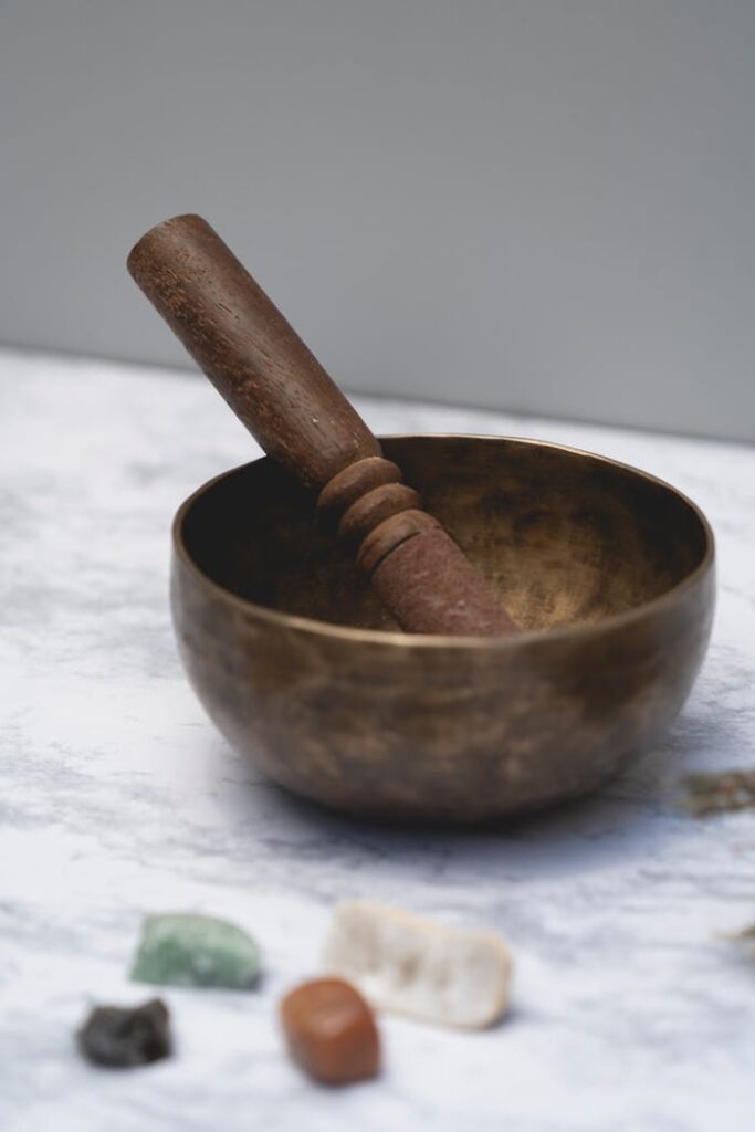 pexels-photo-7947736 Tibetan singing bowl with a mallet surrounded by healing stones on a flat surface.